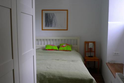 a bedroom with a bed with green and red pillows at Hiša Linhart Apartment in Radovljica