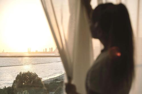 a woman looking out a window at the water at The GrandResort - Limited Edition by Leonardo Hotels in Limassol
