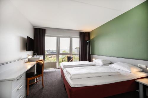a hotel room with two beds and a desk at Good Morning + Bad Oldesloe in Bad Oldesloe