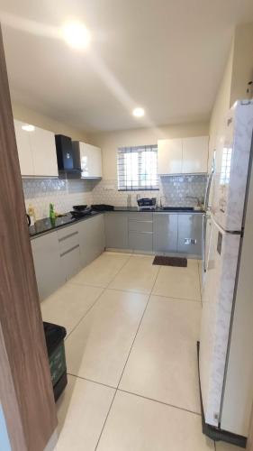 an empty kitchen with white cabinets and a refrigerator at Trinetra Homes 61 in Bengaluru
