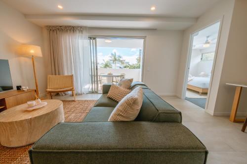 a living room with a green couch and a table at Ocean Verge Apartments in Caloundra