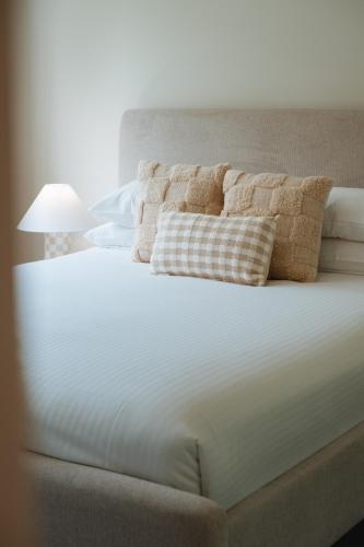 a white bed with two pillows on top of it at Ocean Verge Apartments in Caloundra
