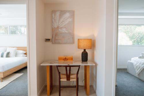 a table with a lamp and a chair in a bedroom at Ocean Verge Apartments in Caloundra