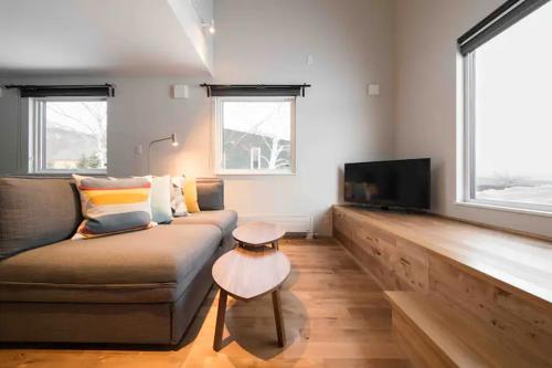 a living room with a couch and a flat screen tv at Momo Niseko in Niseko