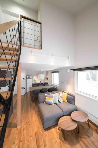 a living room with a couch and a staircase at Momo Niseko in Niseko