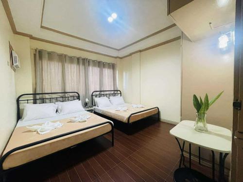 una habitación con dos camas y una mesa en Per Room Booking Host Homes Apitong 3BR Apartelle, en Utap