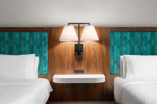 a hotel room with two beds and a light on the wall at Hampton Inn Chicopee - Springfield in Chicopee