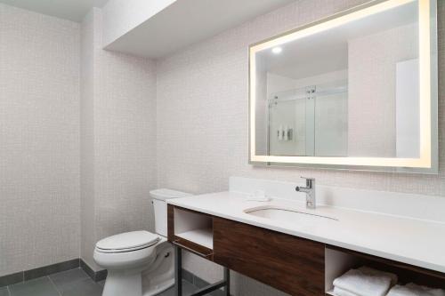 a bathroom with a toilet and a sink with a mirror at Hampton Inn Chicopee - Springfield in Chicopee