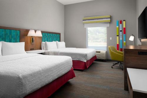 a hotel room with two beds and a television at Hampton Inn Chicopee - Springfield in Chicopee
