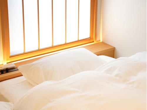 an unmade bed in a room with a window at 大日寺の宿 京都吉祥院 in Kyoto