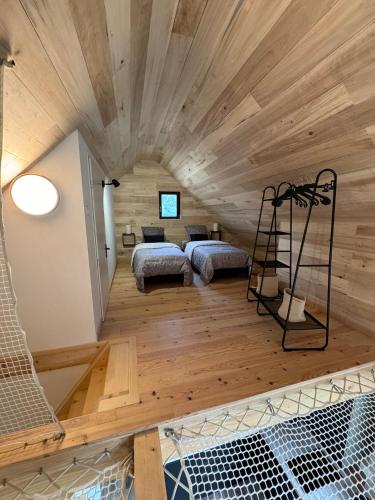 deux lits dans une chambre avec plafonds en bois dans l'établissement Cottage du Mauberme avec bain nordique, à Soulan