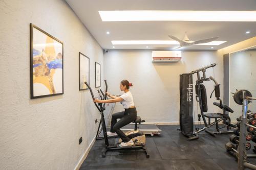 a woman on a exercise bike in a gym at Sukoon by The Ganges with Private Ganga Ghat in Haridwār