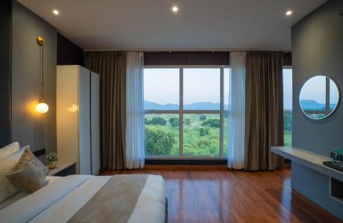 a bedroom with a bed and a large window at Sukoon by The Ganges with Private Ganga Ghat in Haridwār