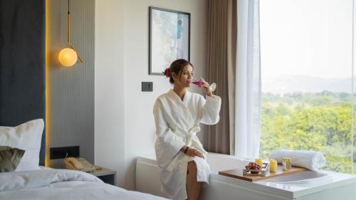 a woman in a robe brushing her teeth in a hotel room at Sukoon by The Ganges with Private Ganga Ghat in Haridwār