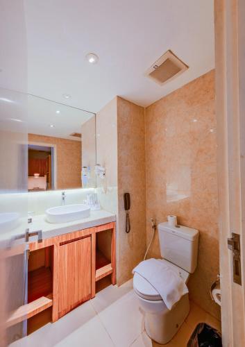 a bathroom with a toilet and a sink at Astara Hotel Balikpapan in Balikpapan
