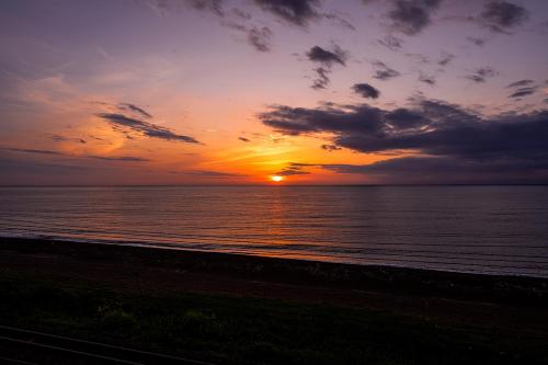a sunset over the ocean with the sun setting at RIZOTIA Kakizaki in Katamachi