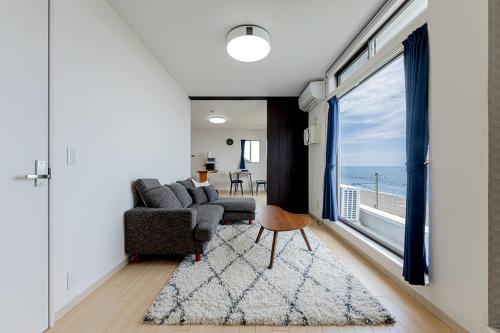a living room with a couch and chairs and a large window at RIZOTIA Kakizaki in Katamachi