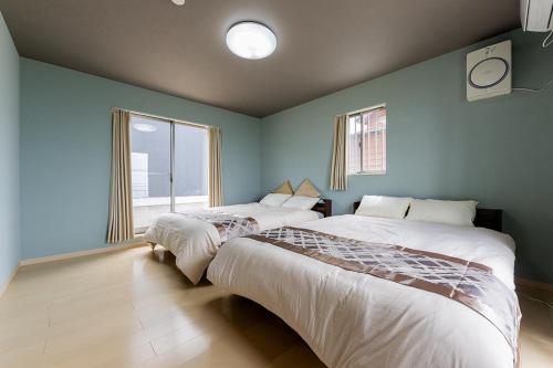 two beds in a room with blue walls at RIZOTIA Kakizaki in Katamachi