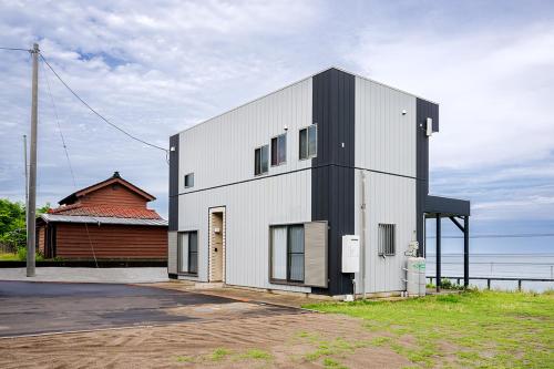 a white and black building next to a house at RIZOTIA Kakizaki in Katamachi