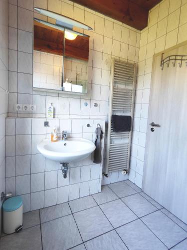 a white bathroom with a sink and a mirror at Ferienhaus kleiner Leuchtturm - Steuerbord Fehmarn Kopendorf - mit Garten und Terrasse in Fehmarn
