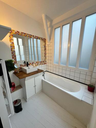 La salle de bains est pourvue d'une baignoire, d'un lavabo et d'une grande fenêtre. dans l'établissement Appartement hyper-centre - Pont Neuf - St Cyprien, à Toulouse