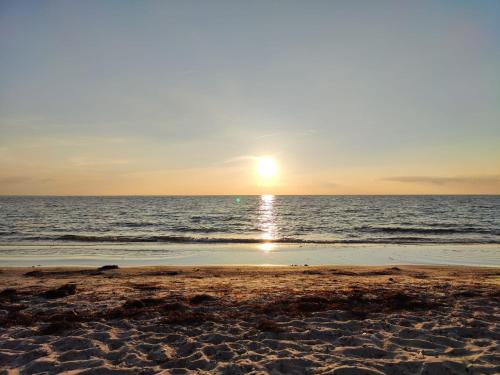 a beach with the sun setting over the ocean at Ferienhaus kleiner Leuchtturm - Steuerbord Fehmarn Kopendorf - mit Garten und Terrasse in Fehmarn