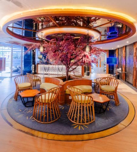 a lobby with tables and chairs and a tree at Astara Hotel Balikpapan in Balikpapan