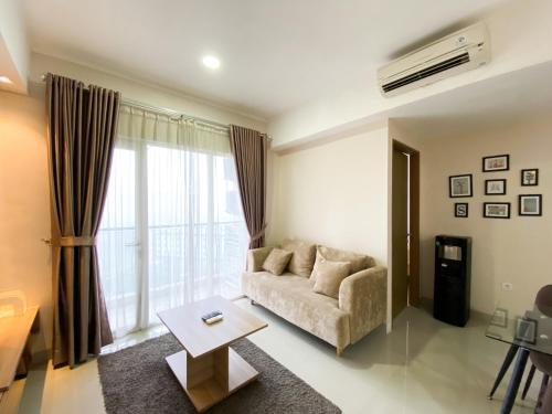 a living room with a couch and a table at Cozy and Minimalist 2BR at 8th Floor The Oasis Cikarang Apartment By Travelio in Cikarang