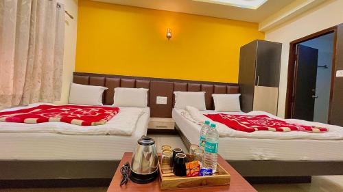 a room with two beds and a table with drinks on it at Hotel Ashapura Palace in Nāthdwāra