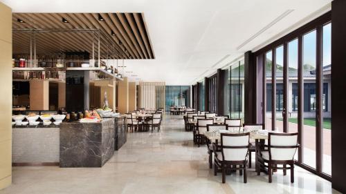 WutaiにあるWutai Mountain Marriott Hotelのテーブルと椅子と窓のあるダイニングルーム