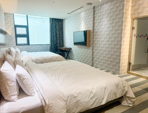 a hotel room with two beds and a television at All-Ur Boutique Motel - Taichung Branch in Taichung
