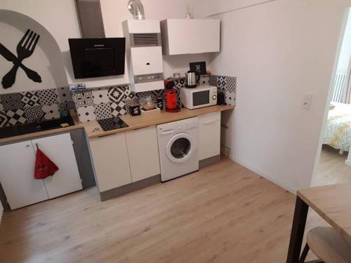 a kitchen with a washing machine and a microwave at COCON du centre ville avec PARKING et WIFI in Millau