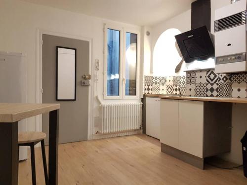 une cuisine avec des armoires blanches et un comptoir dans l'établissement COCON du centre ville avec PARKING et WIFI, à Millau