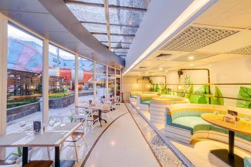 a restaurant with tables and chairs and windows at Astara Hotel Balikpapan in Balikpapan