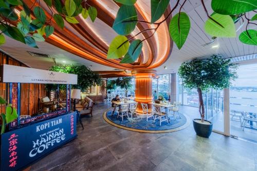 a lobby with a table and chairs and plants at Astara Hotel Balikpapan in Balikpapan