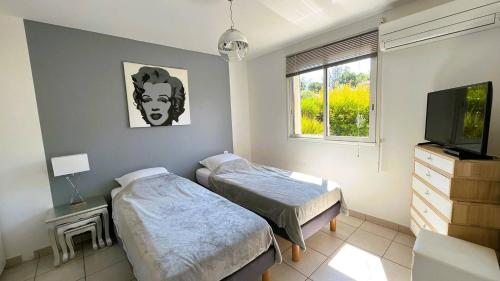 - une chambre avec 2 lits, une télévision et une fenêtre dans l'établissement Appartement Laurel, 4 personnes, piscine, plage à 2 min en voiture, à Lecci