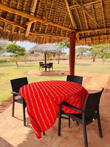 a table with chairs and a red blanket on it at Lake Jipe Eco Lodge in Tsavo West National Park