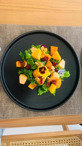 a black plate with a salad on a table at Anzhu Seamate Villa Samui in Amphoe Koh Samui
