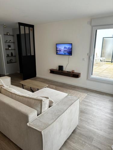 a living room with two couches and a tv on the wall at Appartement cosy et charmant Vert-saint-Denis in Vert-Saint-Denis