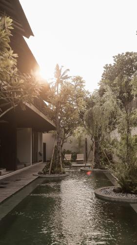 a pool of water with a palm tree next to a building at New Little Ripper Boutique Hotel in Tanah Lot