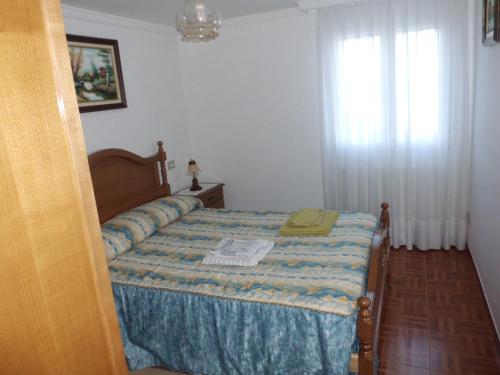 a bedroom with a bed with a blue blanket and a window at Apartamento Casa Jeronimo in Taramundi