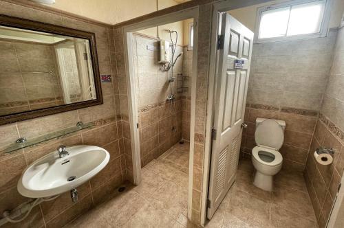 une salle de bain avec un lavabo, des toilettes et un miroir dans l'établissement The Serene House Bangkok, à Bangkok