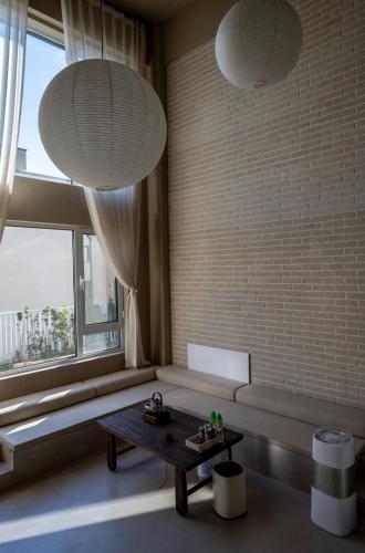 a living room with a bench and two large windows at 无终隅民宿 in Jizhou
