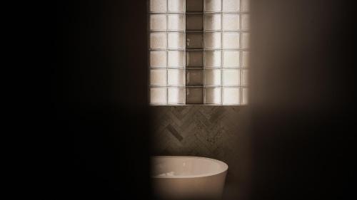 a dark bathroom with a tub and a window at New Little Ripper Boutique Hotel in Tanah Lot