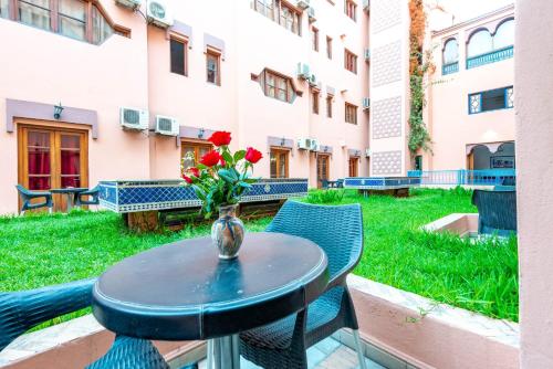 a table with a vase with red roses on it at Hotel Oudaya & Spa in Marrakech