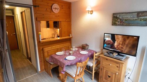 une petite salle à manger avec une table et une télévision dans l'établissement Magnifique studio au pied du télécabine d'Arrondaz et des pistes de ski, à Modane