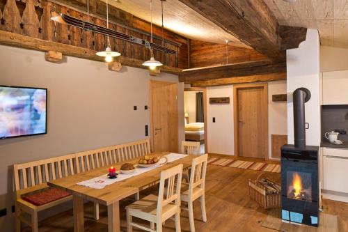 a dining room with a wooden table and a fireplace at Appartements Innerthal in Inneralpbach