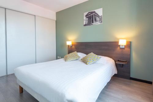 a bedroom with a large white bed with two pillows at Comfort Aparthotel Nimes Centre in Nîmes