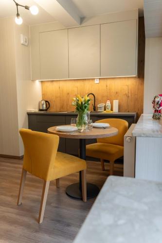 a kitchen with a table with yellow chairs and a table with flowers at Kurort Kozubnik Daglezja - Apartamenty Dream Apart in Porąbka
