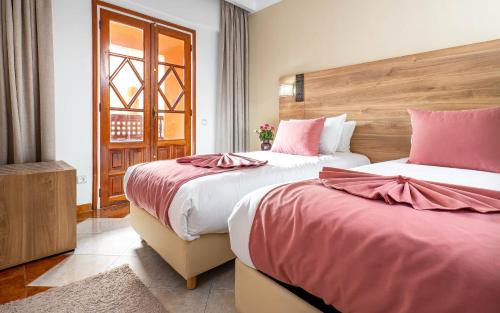 a bedroom with two beds with pink sheets at Hotel Oudaya & Spa in Marrakech